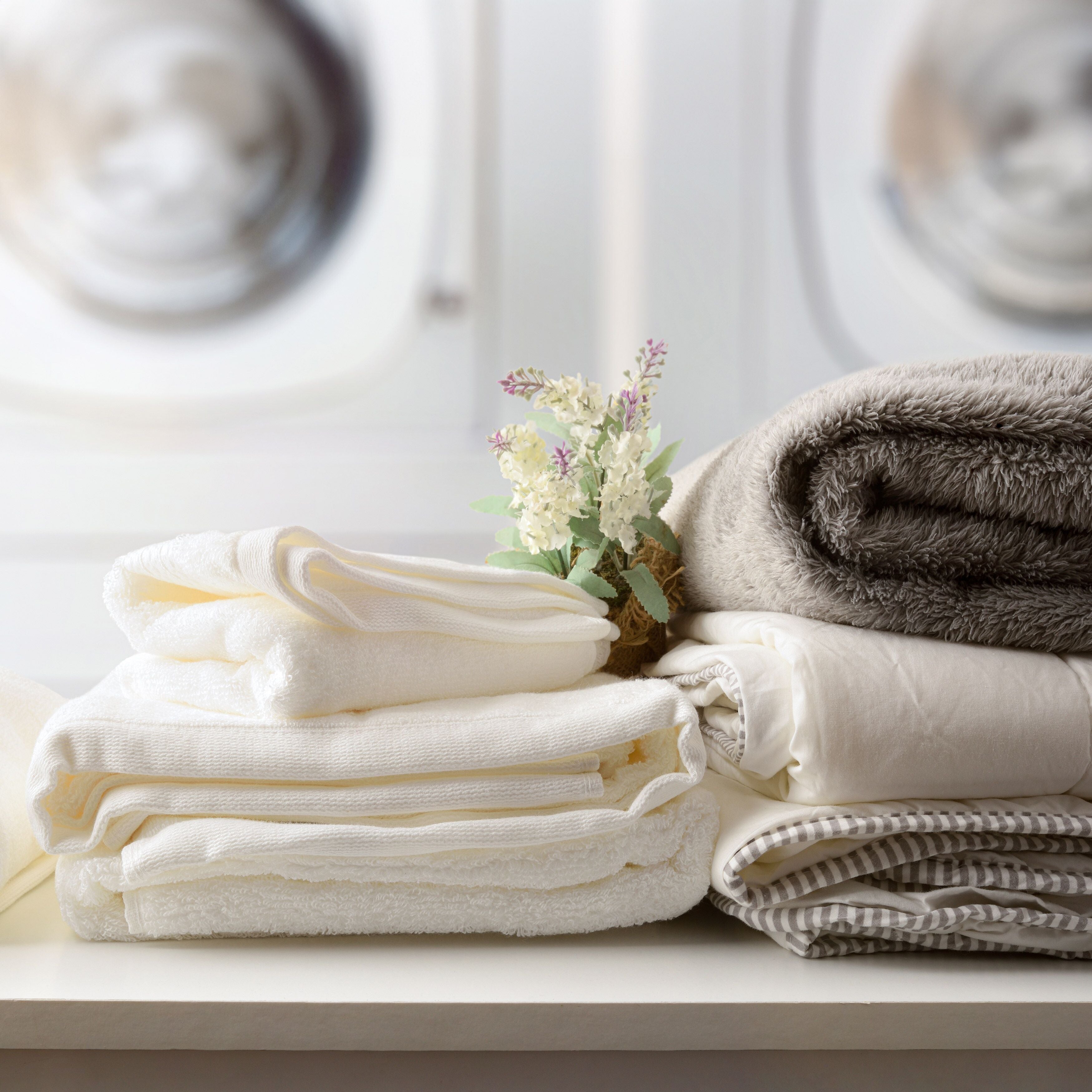 Self-service laundry with textiles on bench and washing machines detail